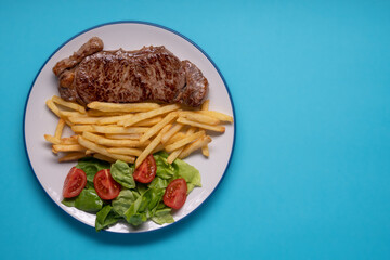 Steak and Fries Overhead on Blue Background