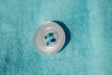 Button sewn on fabric, macro photo.