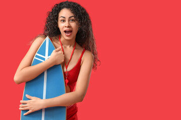 Beautiful young shocked African-American female lifeguard with surfboard on red background