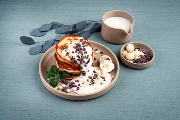 Poster Traditional American Pancakes with banana honey cream, macadamia nuts and chocolate crumbles served as close-up on a Nordic design plate © HLPhoto