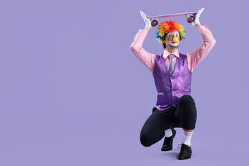 Portrait of clown with skateboard on lilac background. April Fool's day celebration