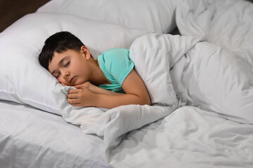 Cute little boy sleeping in bedroom at night