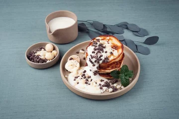 Rolgordijnen Traditional American Pancakes with banana honey cream, macadamia nuts and chocolate crumbles served as close-up on a Nordic design plate © HLPhoto