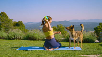 Energetic and playful dog distracts young woman while meditating in the garden