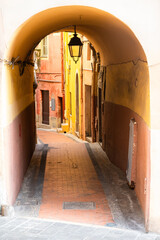 Arcade and a narrow street of the old town of Menton, Provence, France, colorful facades