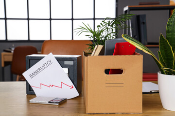 Box with personal stuff on table in office, closeup. Bankruptcy concept