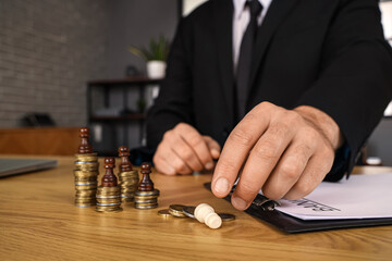 Bankrupt businessman with chess pieces and coins on table in office, closeup