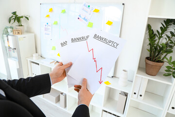 Bankrupt businessman with papers in office, closeup
