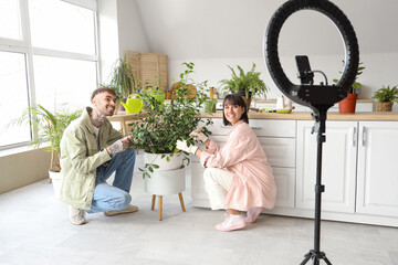 Couple of bloggers with plant recording video at home