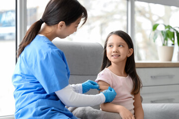 Little Asian girl applying medical patch after vaccination in clinic