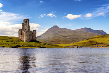 Ruines d'un château écossais qui se reflètent dans les eaux d'un loch et montagnes