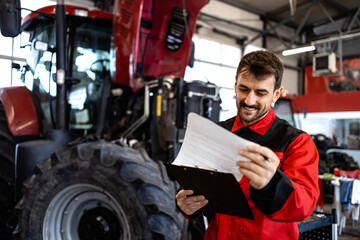Tractor mechanic or serviceman checking work order in workshop.