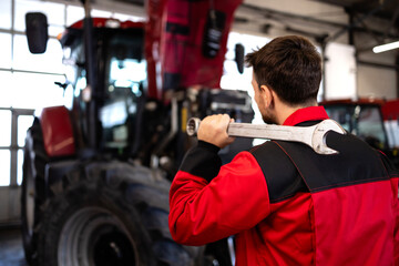 Tractor serviceman or mechanic holding wrench tool ready for work.