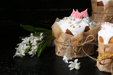 Sweet Easter cakes and beautiful flowers on black background