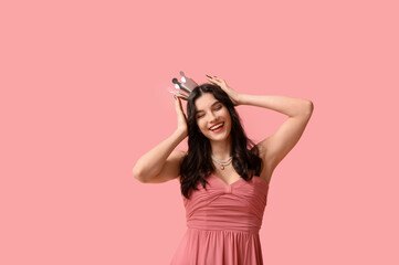 Happy young woman in stylish prom dress and paper crown on pink background