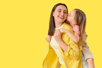 Young woman with her cute little daughter on yellow background. Mother's Day celebration