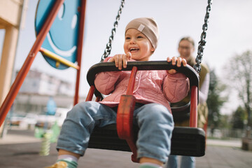 Smiling toddler girl having fun on a swing