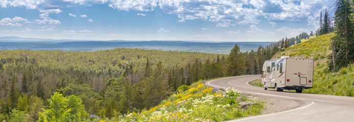 Banner of Camper Driving Down Road in The Beautiful Countryside Among Pine Trees and Flowers. - 786688613