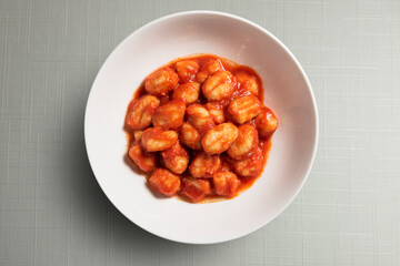 White bowl with tomato potato dumpling