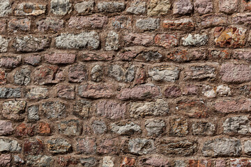 Stone texture of a wall in Montenegro. An ancient wall made of brown coloured stones. Background. Template. For design. Horizontal.