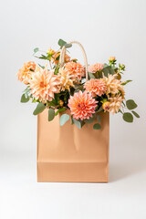 Brown shopping bag holding dahlia flowers.