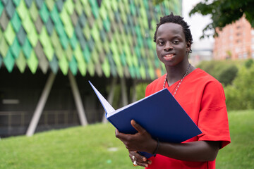 Man Holding Blue Book in Front of Building