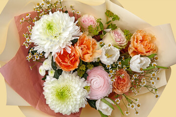 Beautiful bouquet composed of different flowers on a yellow background