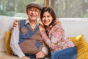 Portrait of beautiful Latin woman hugging her older father smiling and looking at camera.