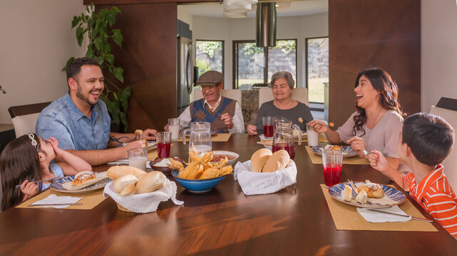Latin family different generations enjoy thanksgiving food.