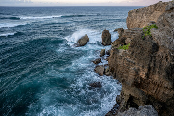 The rough turquoise waters of the Pacific Ocean carve out jagged cliffs from the volcanic rock...