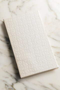 white decorative embossed paper on handmade book on white marble table
