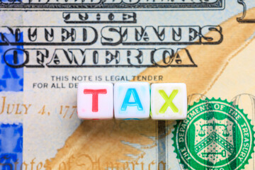 A stack of white cubes spell out the word tax on top of United States of America bill