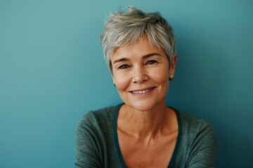 Portrait of a smiling senior woman with grey hair against a blue background