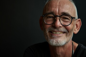 Portrait of a happy senior man in glasses on a dark background.