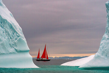 Red sailboat between two icebergs in Ilulissat Greenland - obrazy, fototapety, plakaty
