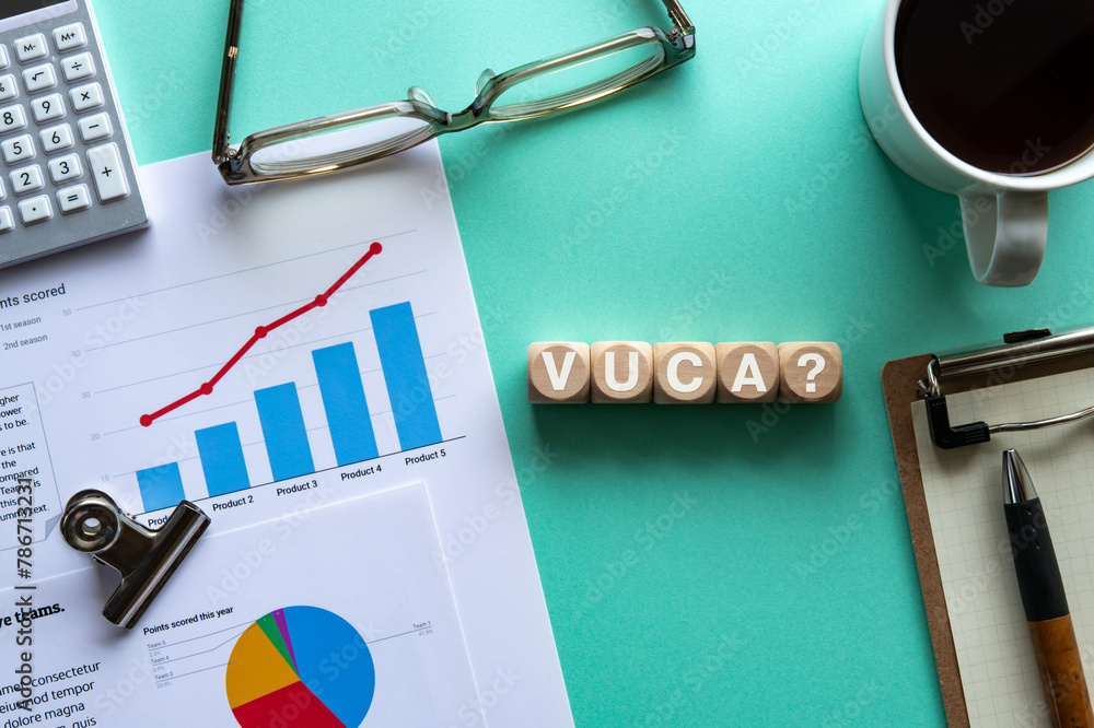 Poster there is wood cube with the word vuca. it is an abbreviation for volatility, uncertainty, complexity