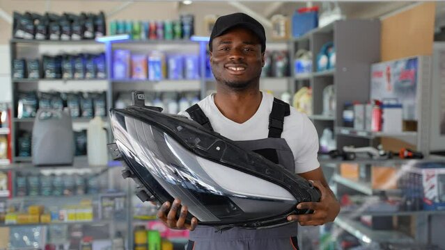 Portrait of black seller with automotive headlight in auto parts store