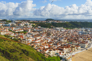 Lush greenery frames the dense urban landscape of Nazare, leading to the beach and ocean... - 786721246