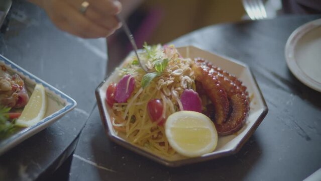 mano en plato de platillo Thailand&eacute;s con pulpo