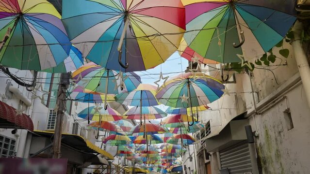 Colorful decoration umbrellas hang overhead above a walking pedestrian street in George Town, Penang, Malaysia