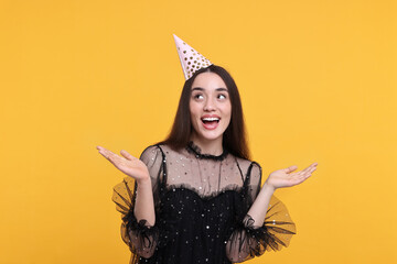 Happy woman in party hat on orange background