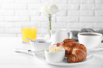 Fresh croissant and butter on white wooden table. Tasty breakfast