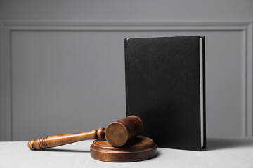 Law. Book, gavel and sound block on light table against gray background