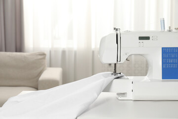 White sewing machine and fabric on table indoors, closeup
