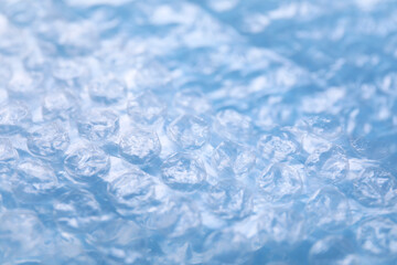 Transparent bubble wrap on light blue background, closeup