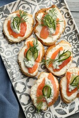 Tasty canapes with salmon, cucumber, cream cheese and dill on table, top view