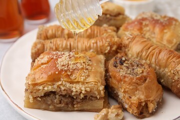 Eastern sweets. Pouring honey onto pieces of tasty baklava on table, closeup