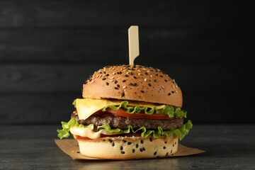 Burger with delicious patty on gray table against dark background