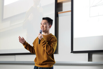 Student giving a presentation speech in front of a projector screen in a room