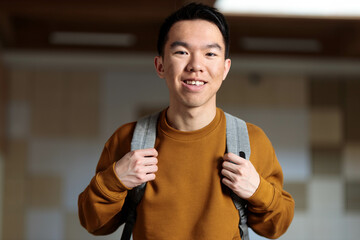 Young student in brown sweater with backpack, happy and ready for school